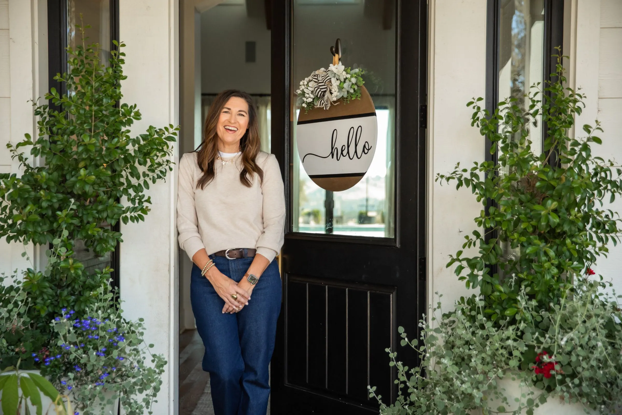 Kelly laughing in the doorway beside a hello sign
