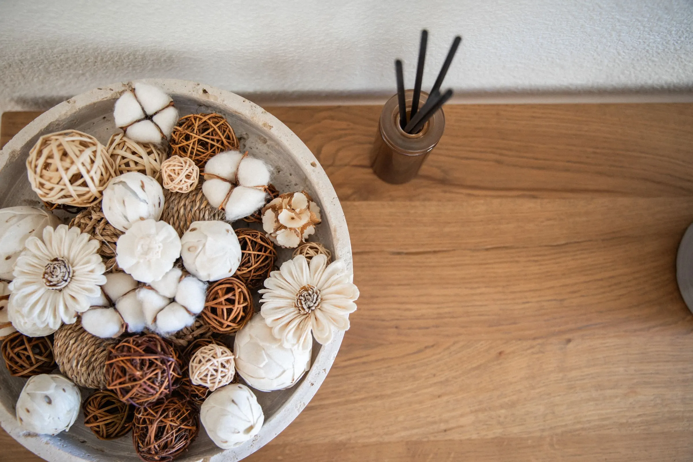 A stone bowl of dried flowers on a wooden table