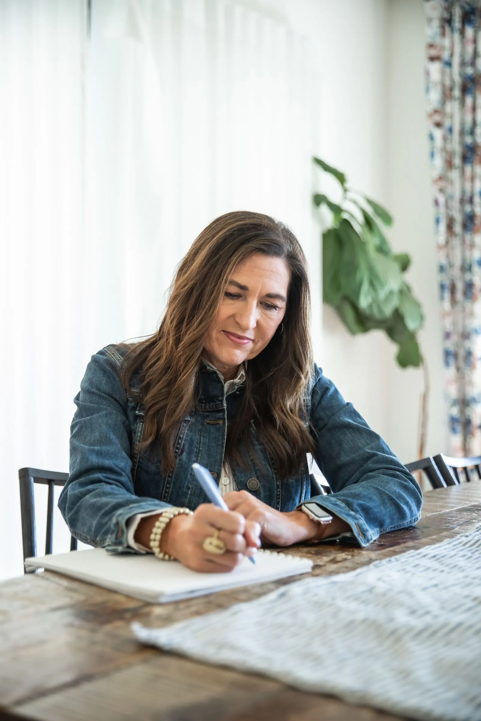 Kelly writing in a notebook at a wooden table